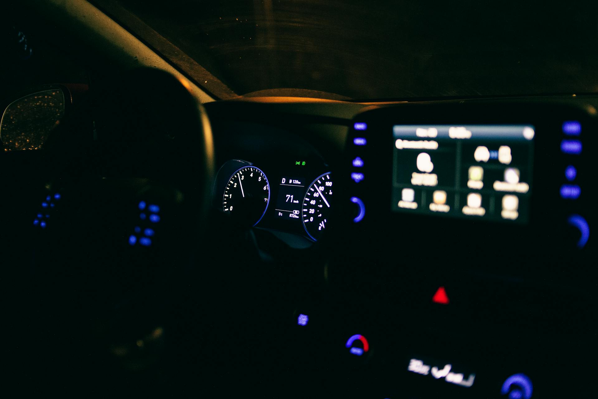 Close-up of a modern car's illuminated dashboard and digital screen during nighttime driving.