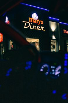 透过汽车挡风玻璃，能看到城市里一家现代餐厅发光的招牌，映衬着漆黑的夜晚