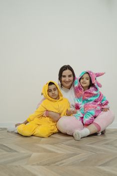 一位快乐的母亲和两个穿着舒适动物服装的孩子在室内微笑着坐在一起