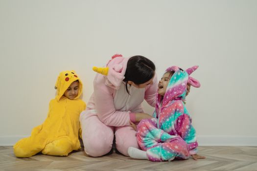 一位母亲和孩子们穿着可爱的动物连体衣在室内玩耍