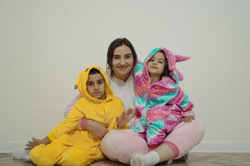 Free Happy family with kids in colorful animal onesies sitting together and smiling at home. Stock Photo