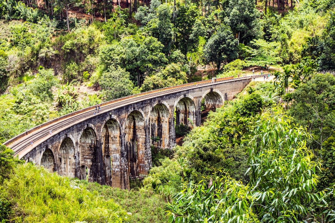 People Walking on Bridge With Railroad during Day