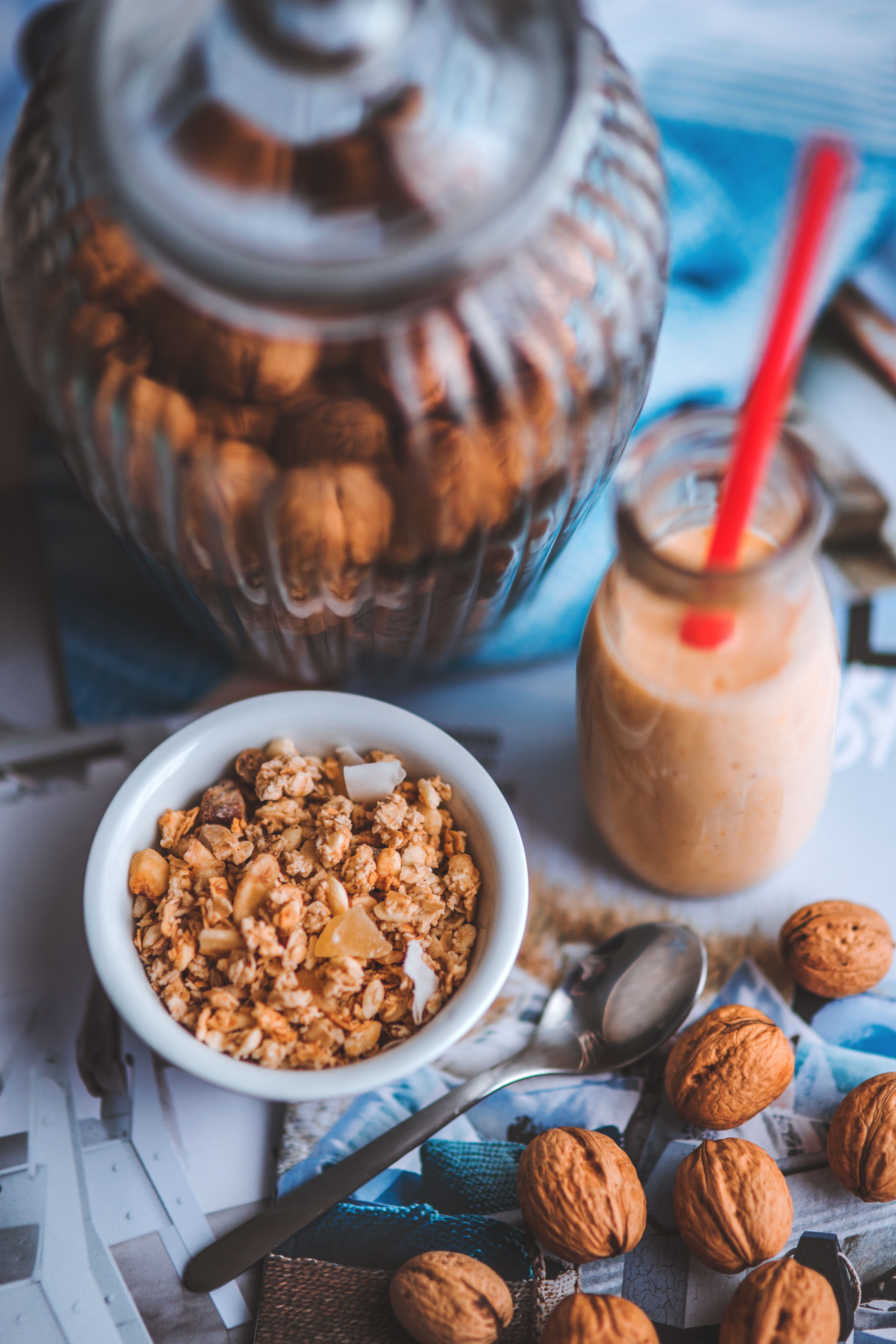 Top view of a bowl of muesli with nuts and a smoothie, ideal for healthy breakfasts.