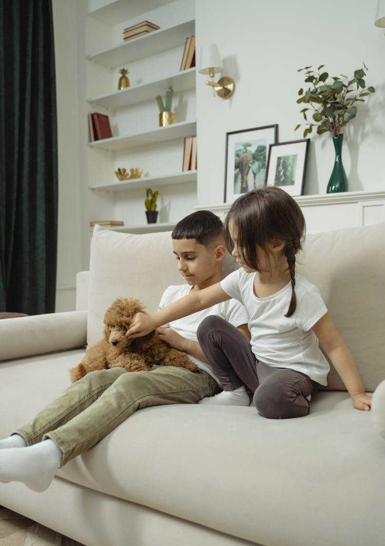 A Boy And Girl Sitting On The Sofa With A Dog 