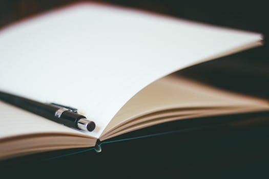 Close-up view of an open notebook with a pen resting on it, ideal for writing.