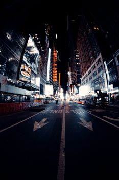 Illuminated signboards on modern buildings near asphalt road in city district at night