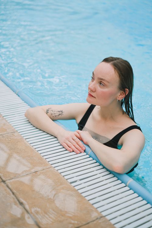 Free Young woman with tattoos relaxing at a poolside, enjoying leisure time. Stock Photo