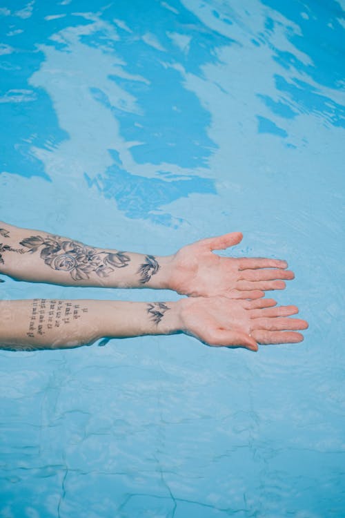 Tattooed Arms in Blue Water 