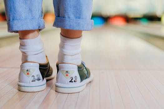 Close-up shot of a person wearing bowling shoes on a bowling lane, perfect for leisure themes.