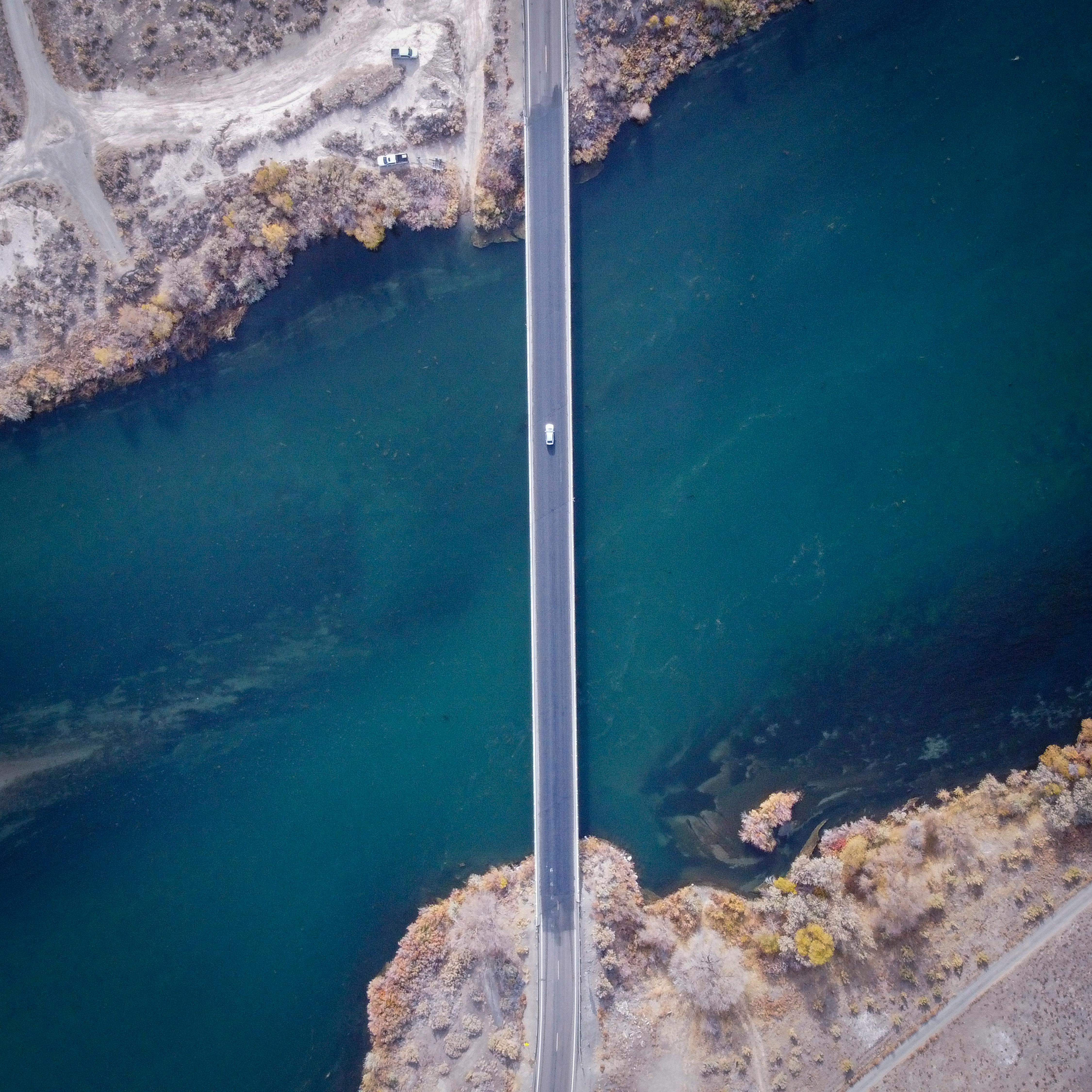Aerial View of Car Driving on Highway Bridge Above Sea
