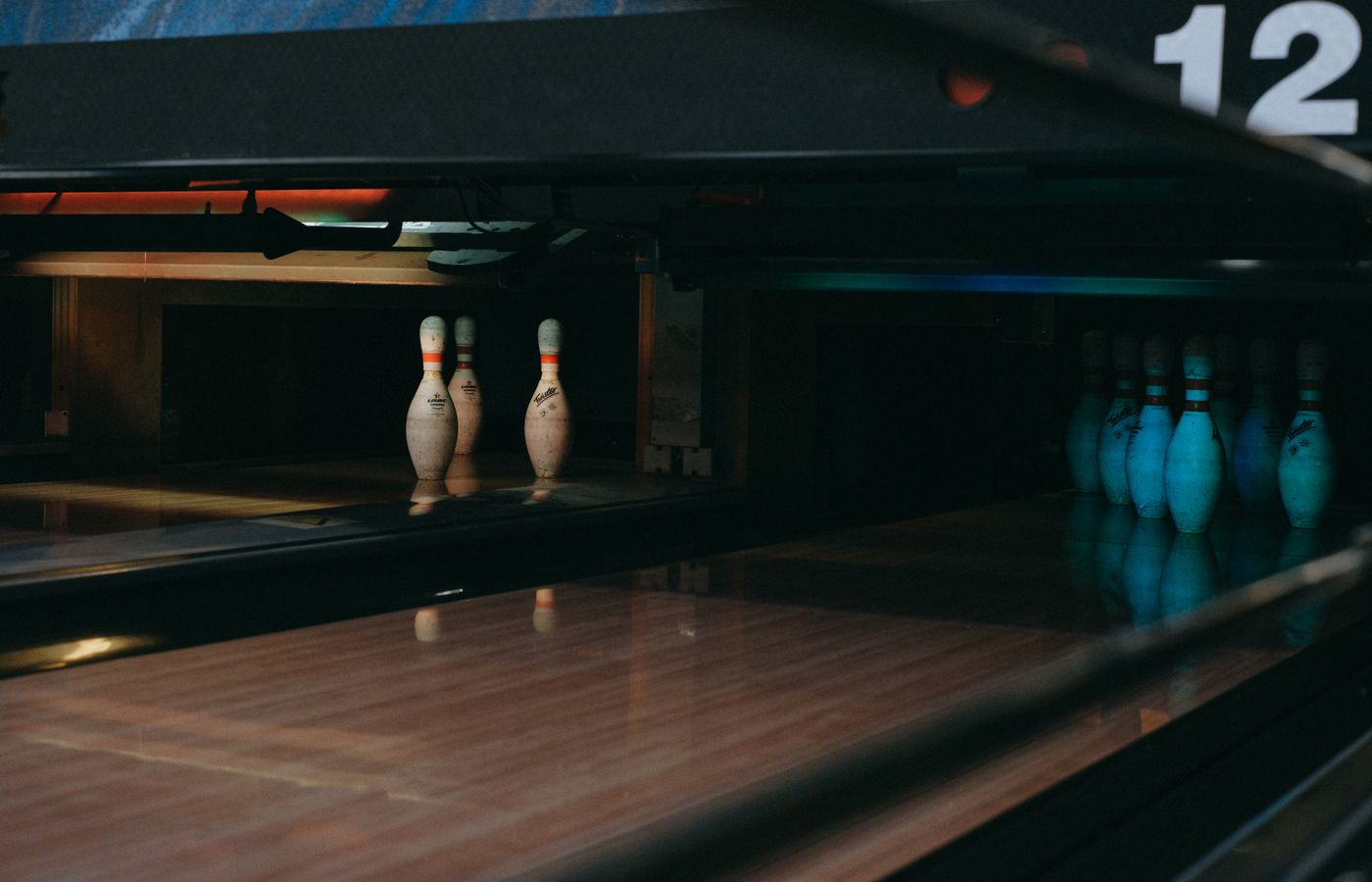 A dimly lit bowling alley showcasing lined-up pins ready for a strike.