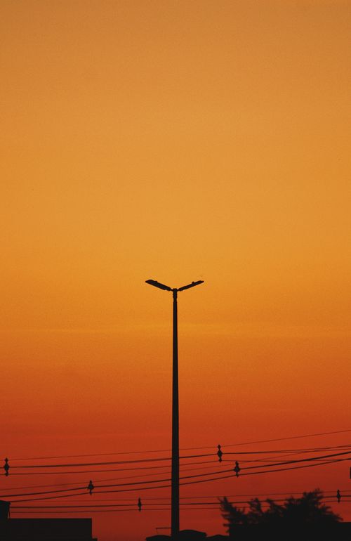 Free A streetlight silhouette against a vibrant orange sunset sky. Stock Photo