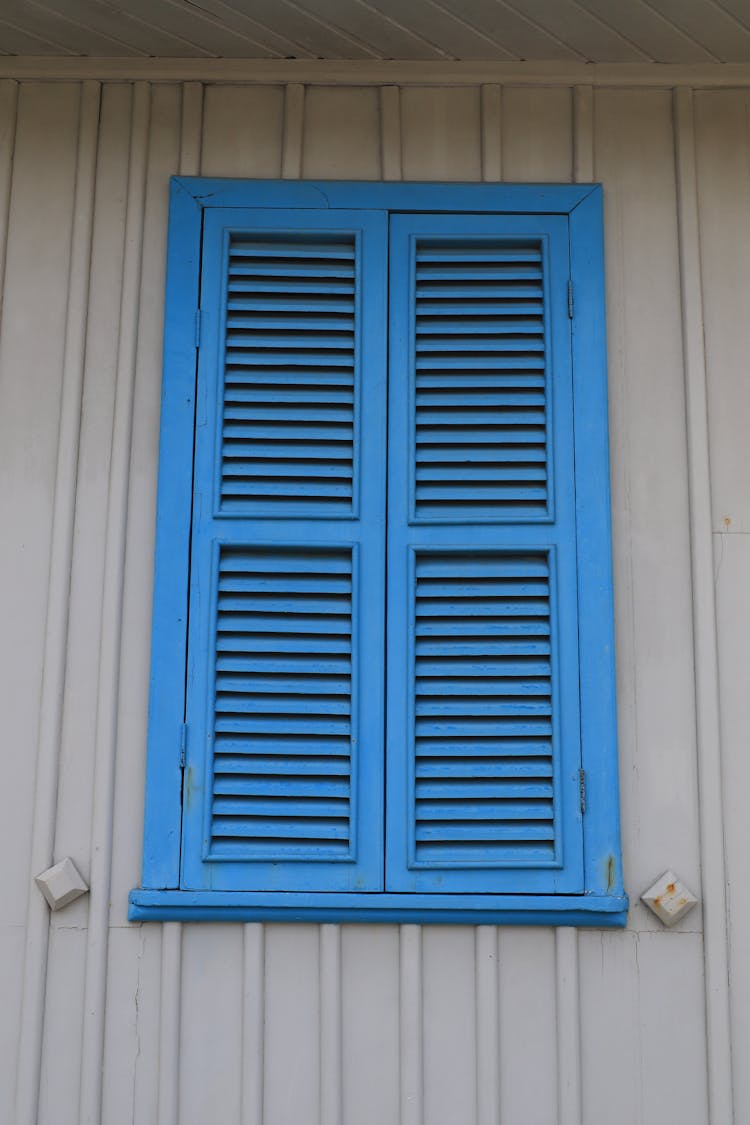 Blue Window Shutters On Wooden House