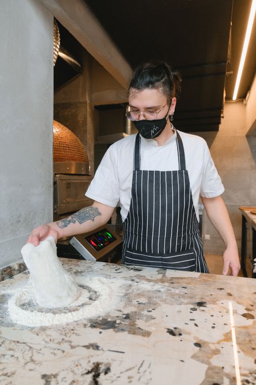 Free A masked baker in an apron skillfully kneading dough on a kitchen countertop. Stock Photo
