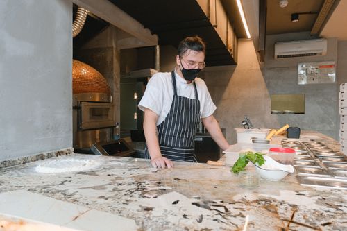 Free Chef wearing a mask in a modern kitchen setting, preparing ingredients for baking. Stock Photo