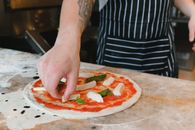 Person Holding Pizza With Green Leaves