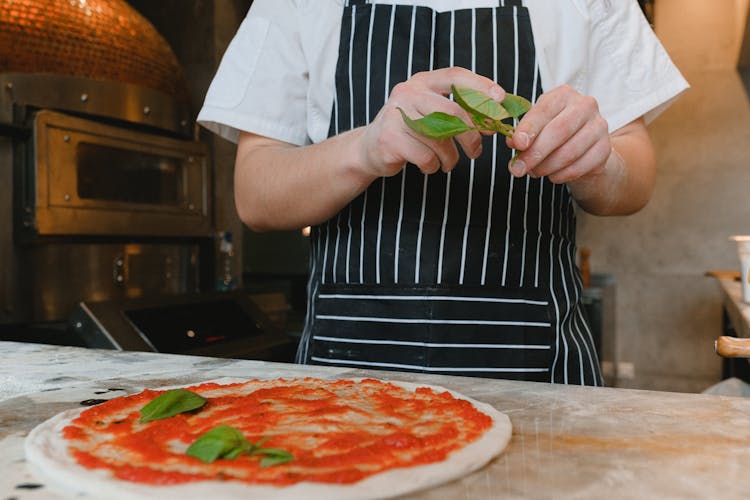 Man Making A Pizza And Holding Green Leaves