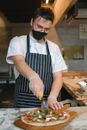 Man in White Shirt and Black Apron Holding Knife Slicing Food