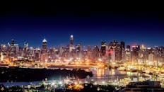 令人惊叹的夜间城市景观中，照明的摩天大楼和热闹的城市天际线倒映在一条宁静的河流上