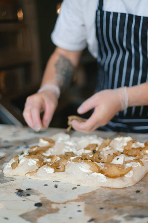 A Man Putting the Pizza Toppings