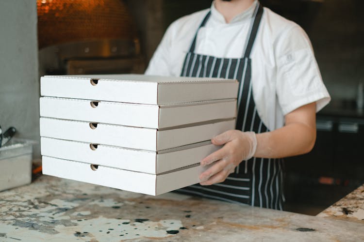 A Person Holding Boxes Of Pizza