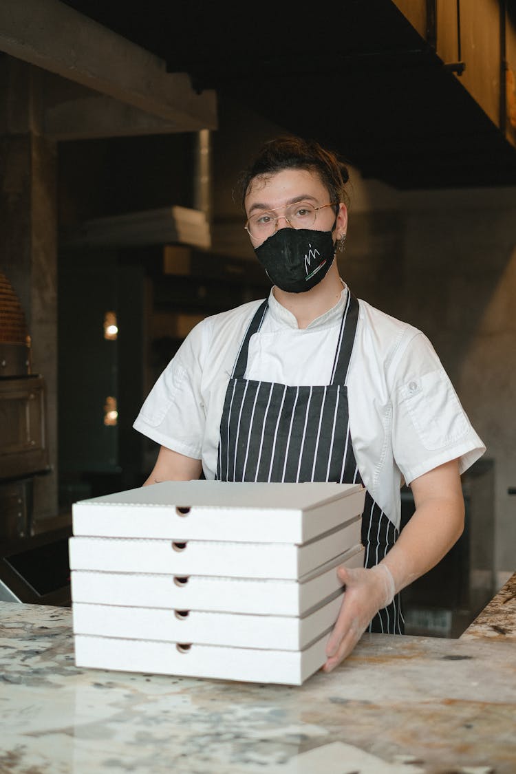 Cook In Kitchen Holding Pizza Boxes 