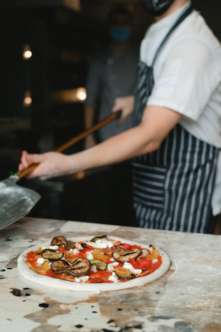 A Chef Using A Pizza Peel In Cooking Pizza