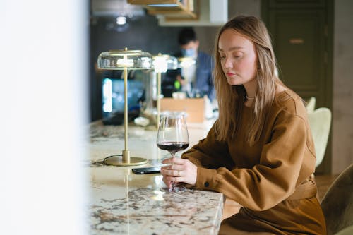 A Woman in Brown Dress Drinking Red Wine