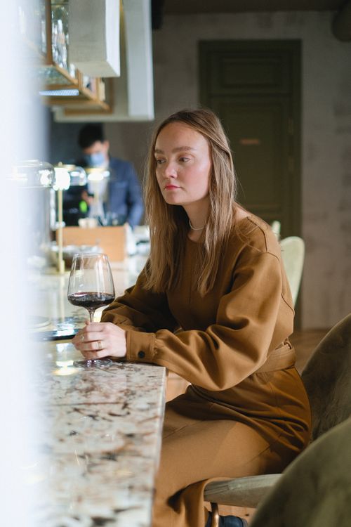 Free A woman enjoys wine in a chic restaurant setting, exuding tranquility and style. Stock Photo