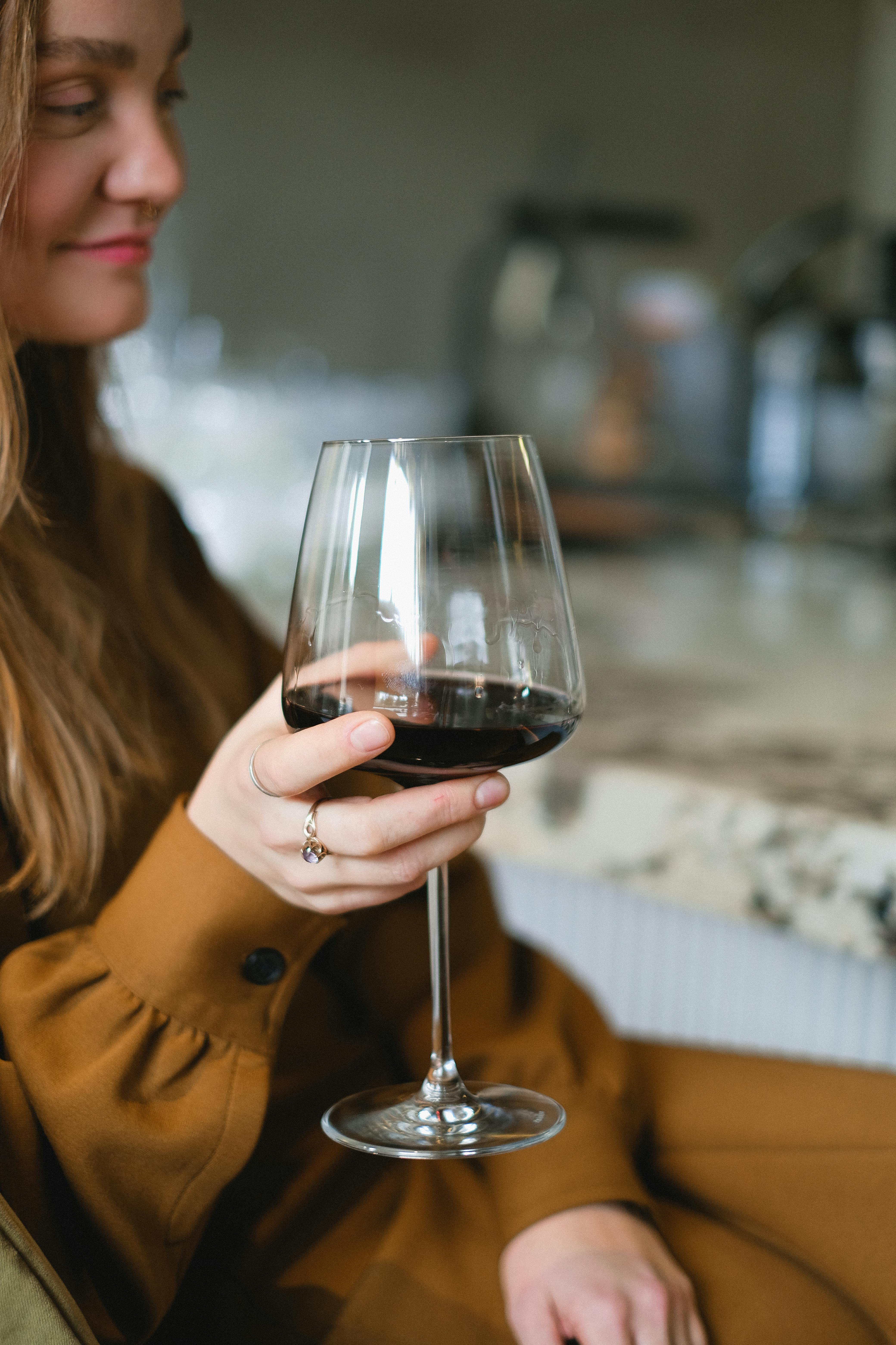 a woman in brown dress holding a glass of red wine