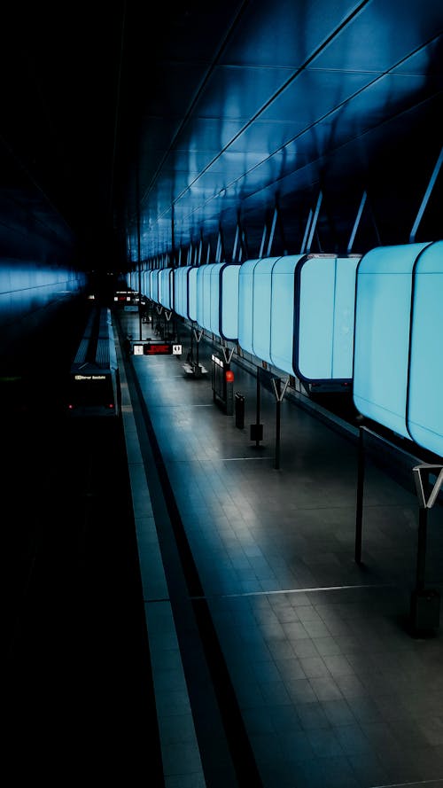 Empty modern subway station with illuminated neon lamps with blue light hanging from ceiling