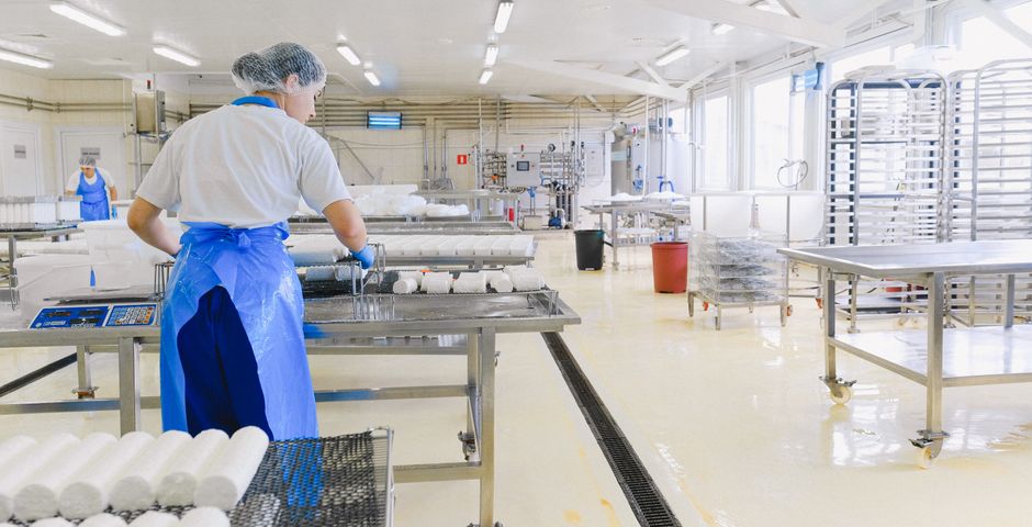 A worker in protective gear handling food in a production facility — pests here are a halal-integrity risk
