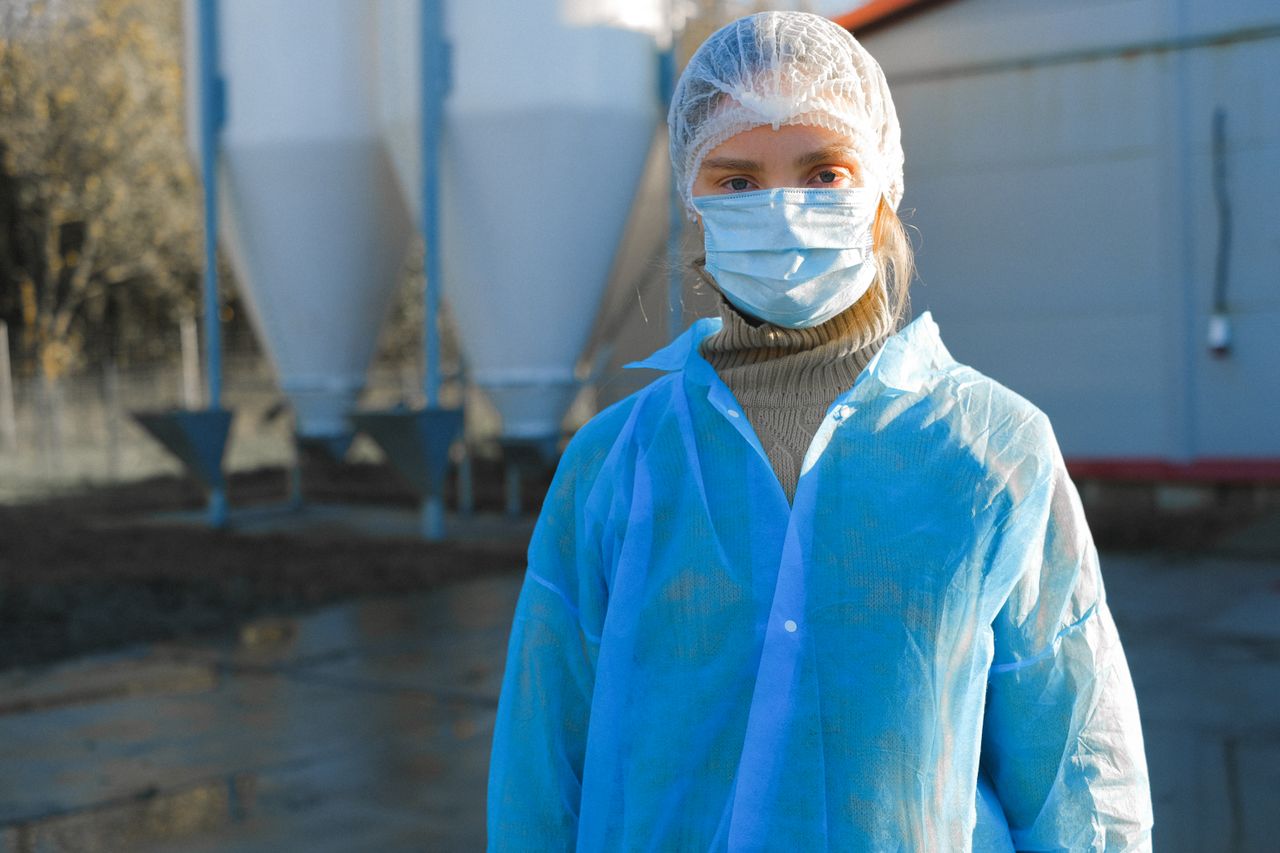 a woman wearing protective clothing including a mask and hair net outd