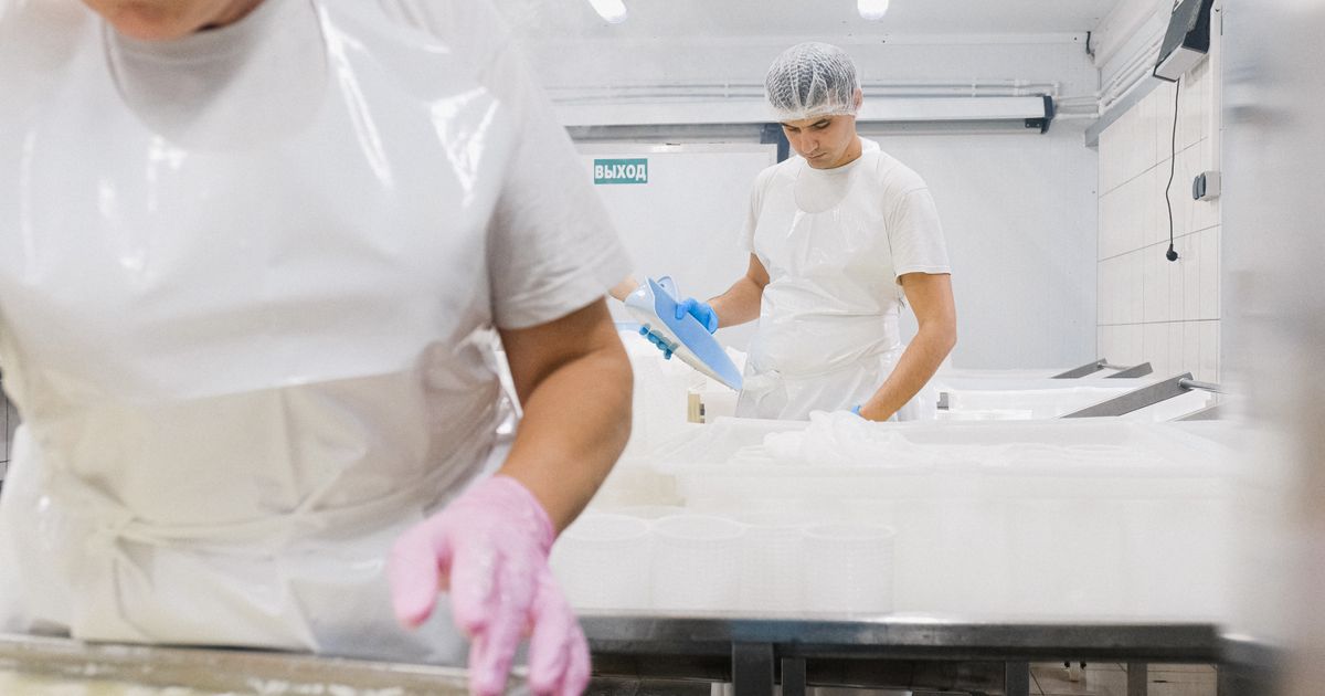 Mitarbeiter in Schutzkleidung bei der Reinigung einer Produktionslinie in der Lebensmittelindustrie