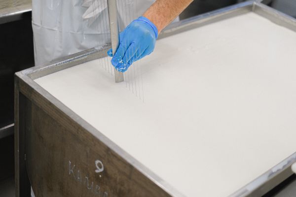 Worker using tool in cheese production