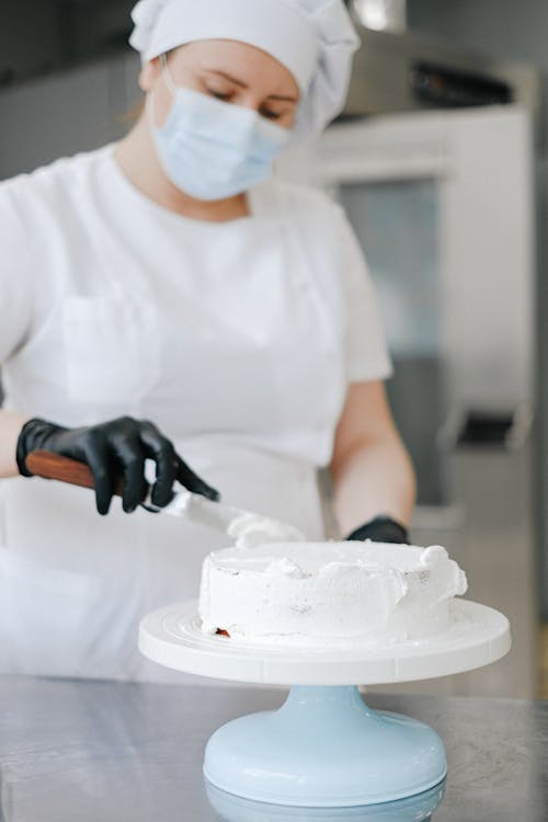 Woman Spreading Cream on a Cake in a Bakery 