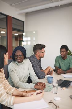 Multi-ethnic team discussing work at modern office table. Collaboration and teamwork concept.