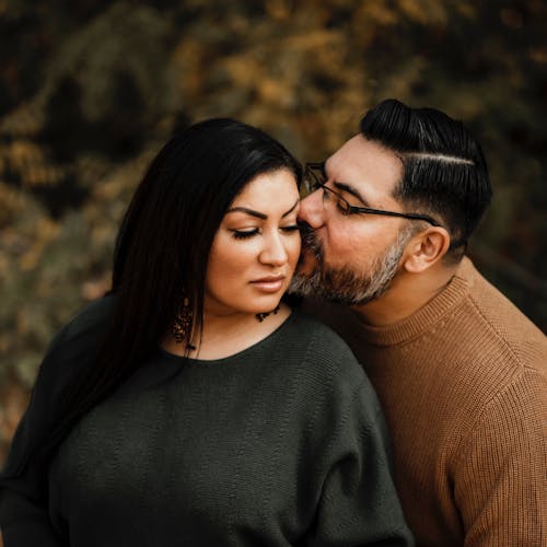 Bearded Man in Brown Sweater Kissing Woman in Black Sweater