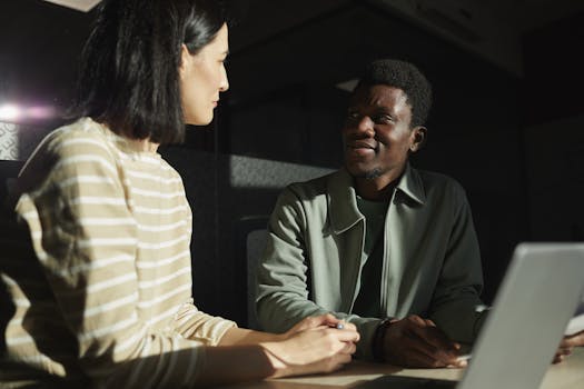 Two colleagues engaged in a thoughtful discussion, highlighting diversity in a modern office setting.