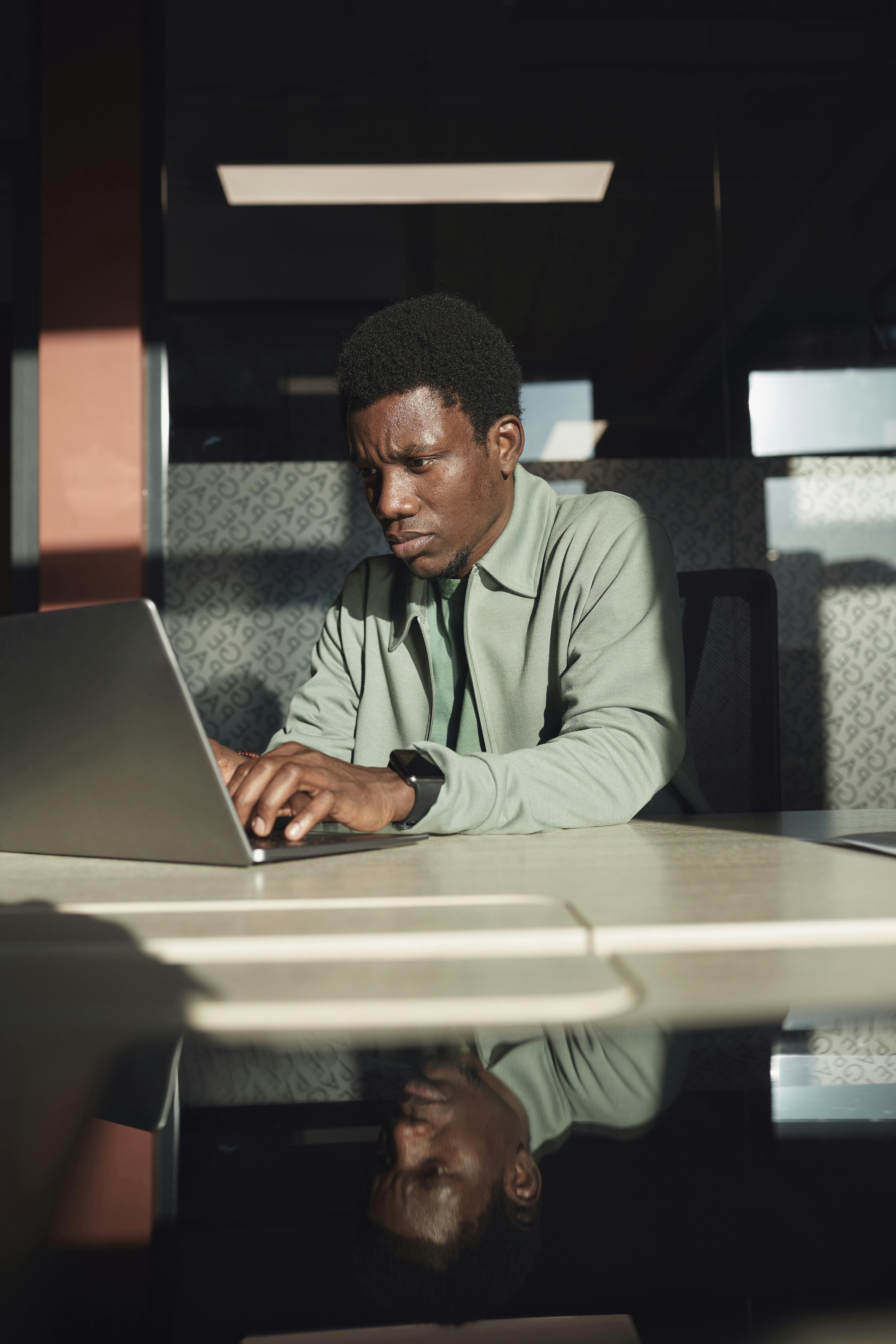 Man concentrating on laptop at indoor workspace, reflecting innovation.