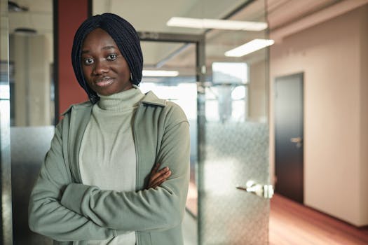 A woman stands confidently with arms crossed in a modern office environment.