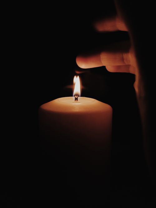 Free A hand lights a candle, creating a warm glow in the dark. Perfect for themes of warmth and tranquility. Stock Photo