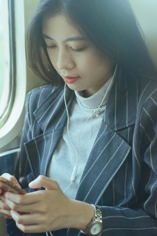 Free Stylish young woman in West Java using a smartphone on a train journey. Stock Photo