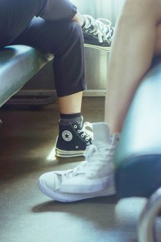 Close-up image of casually seated individuals showcasing stylish sneakers indoors.
