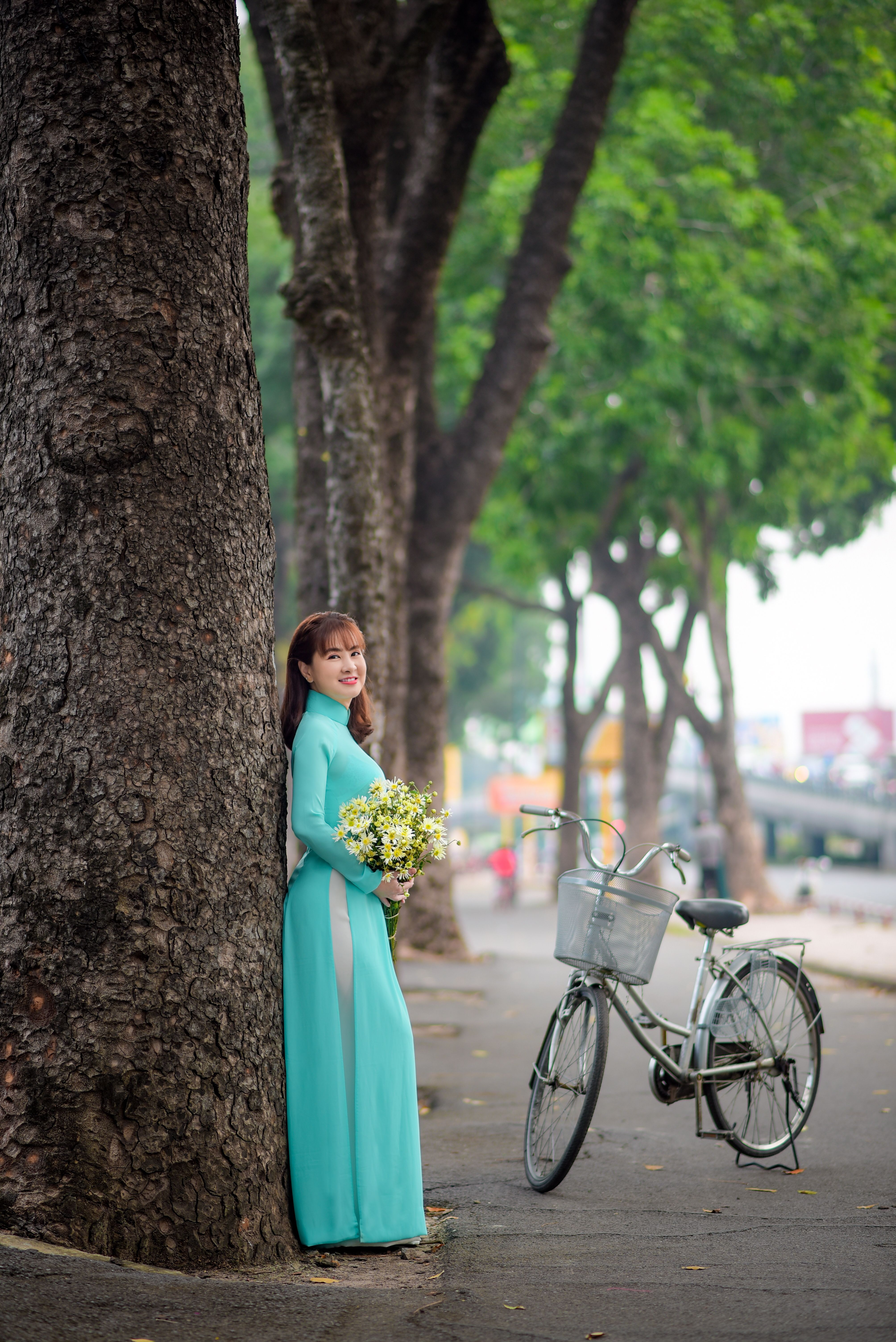 Woman in Traditional Dress Standing Beside a Tree Trunk · Free Stock Photo