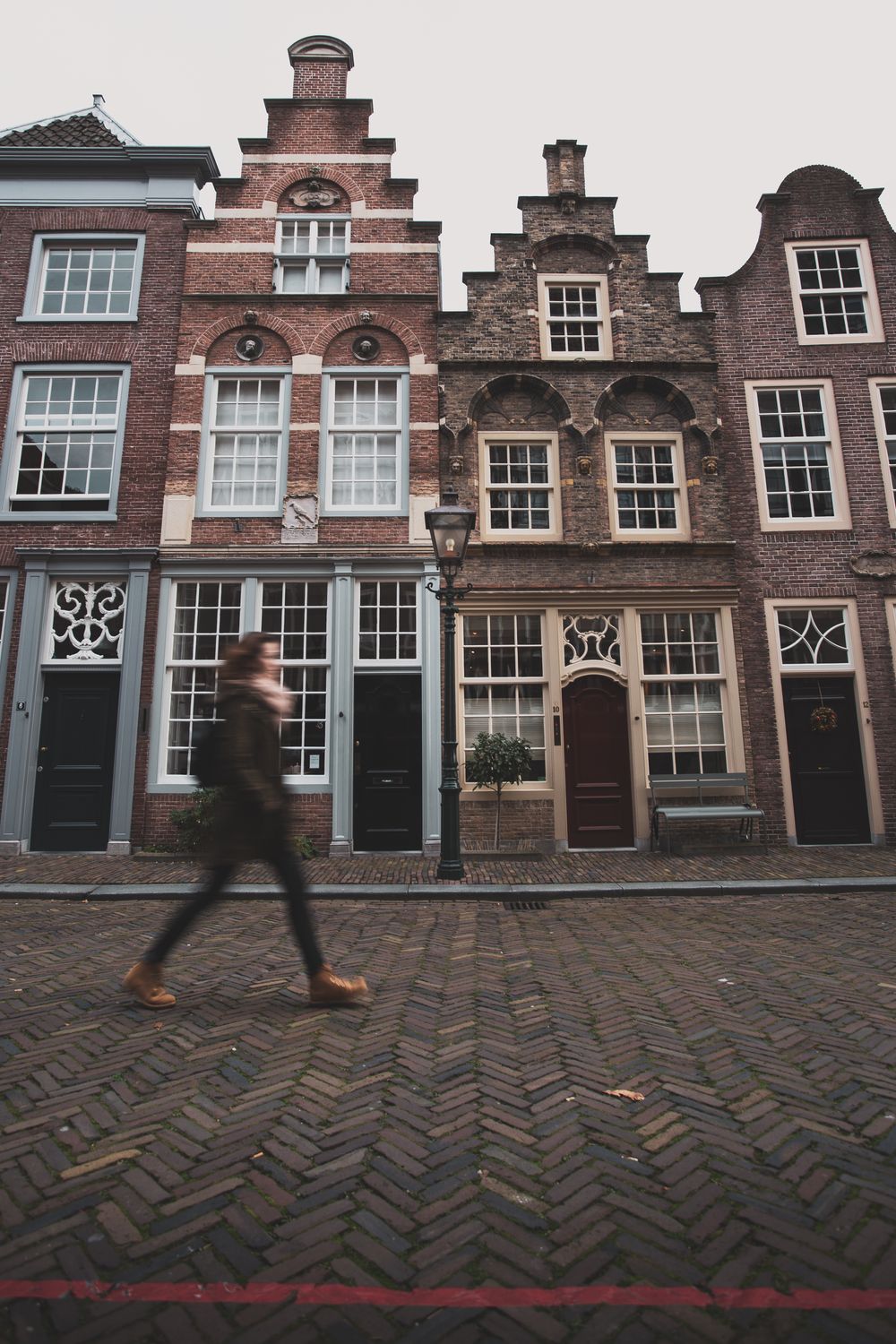 Pedestrian walking on brick-paved European street with historic gabled facades in the Netherlands Pedestrian walking on brick-paved European street with historic gabled facades in the Netherlands