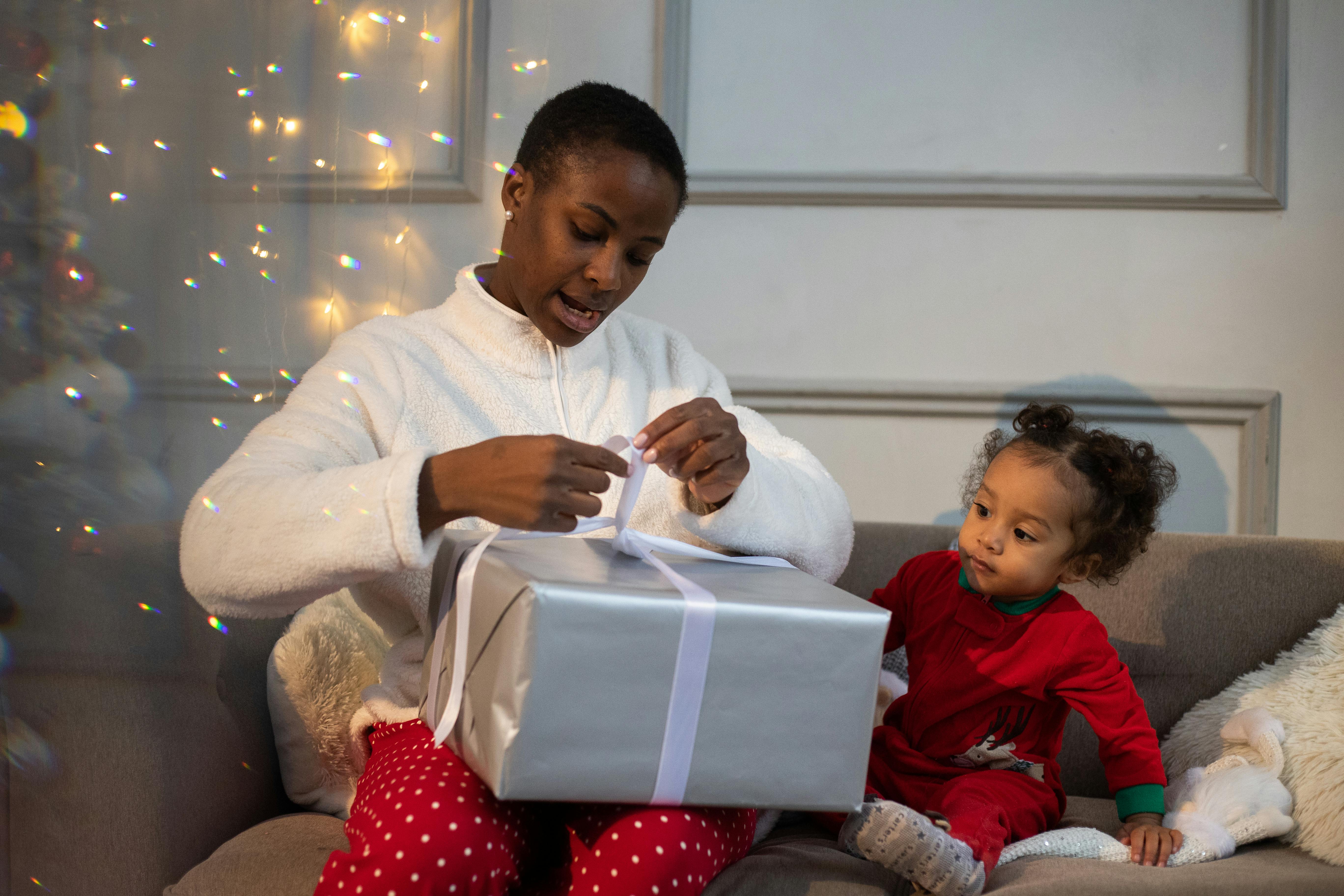 a woman tying the ribbon of a gift with her child