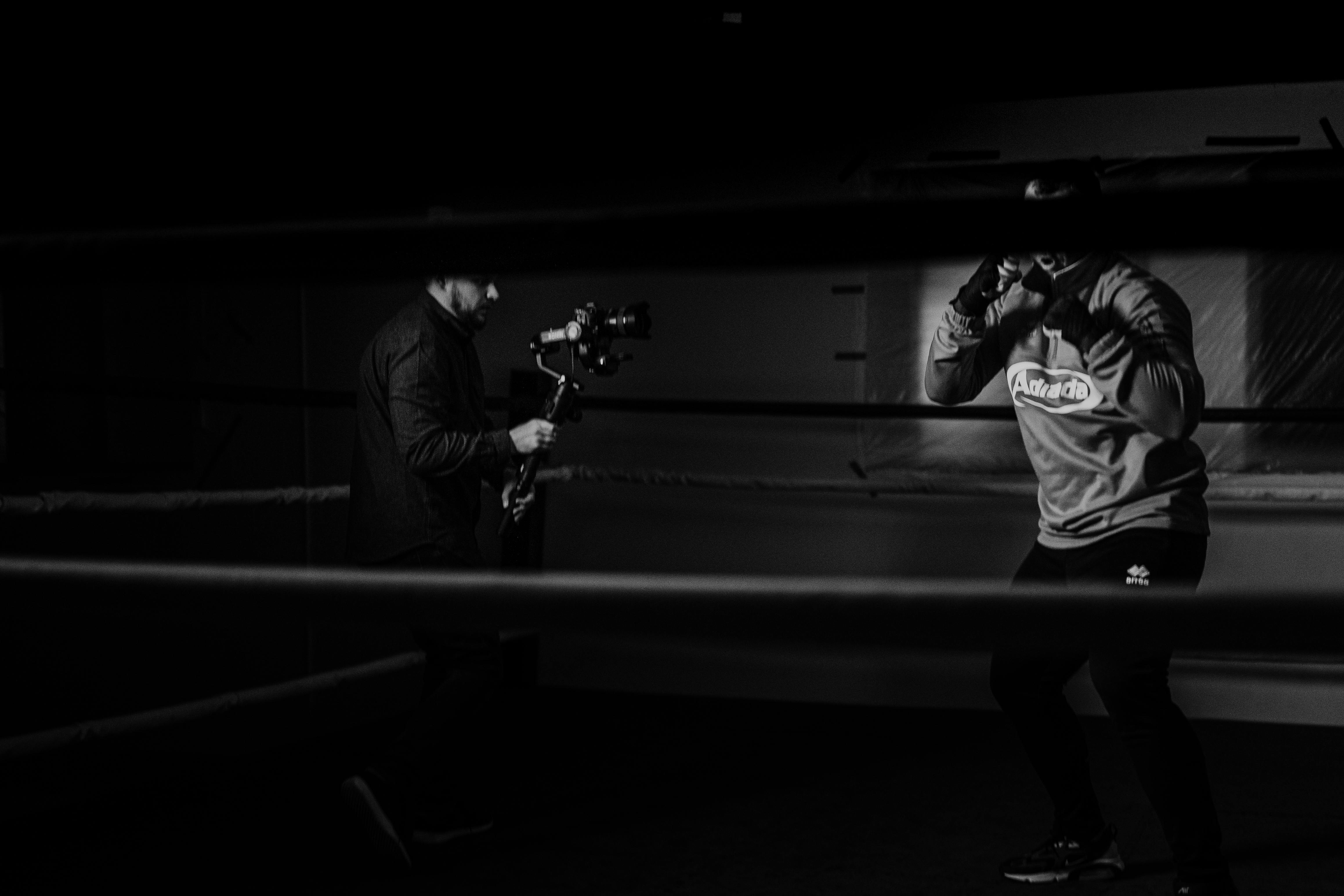 unrecognizable boxer and partner with camera during training in ring