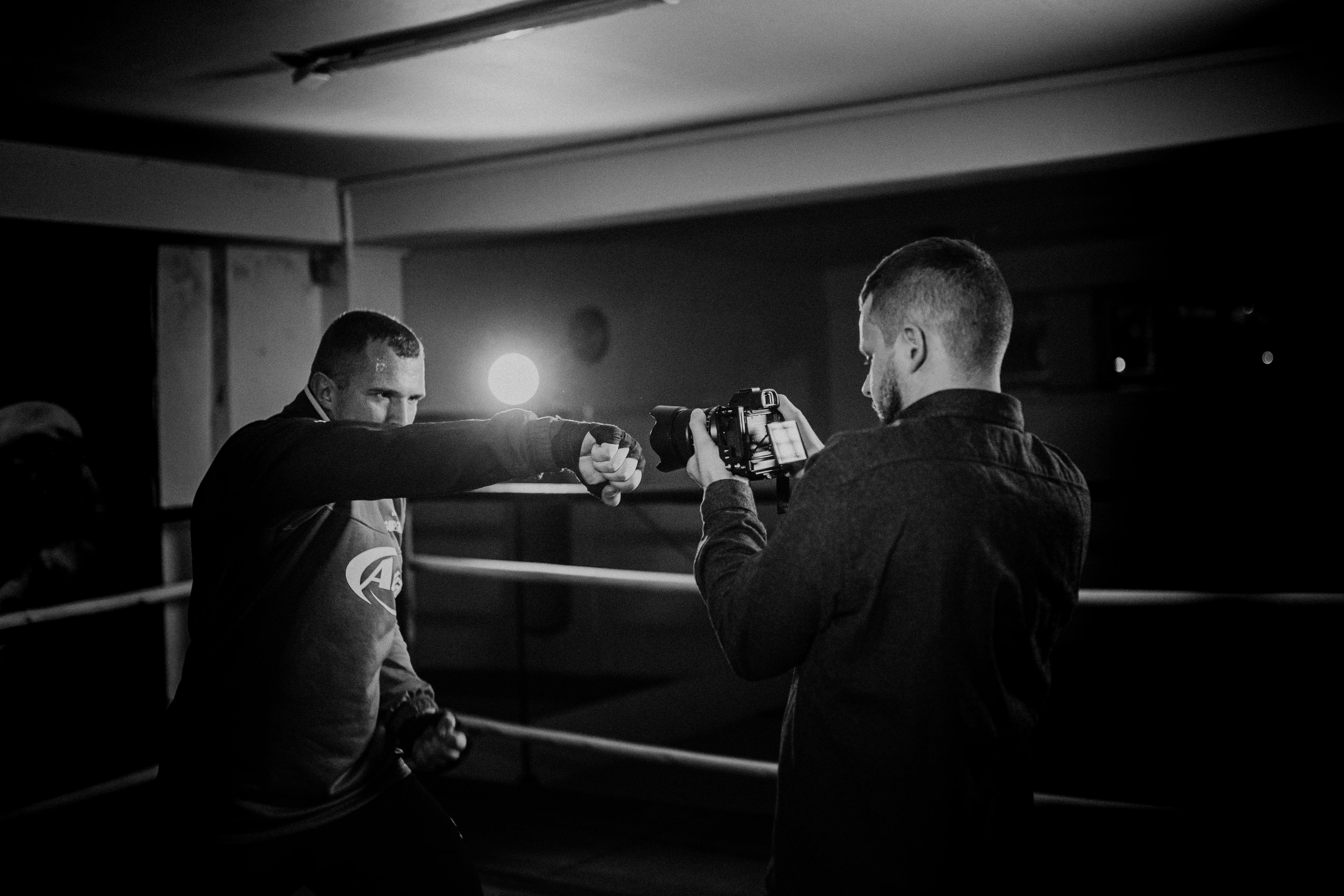 powerful boxer showing punch technique against friend with camera