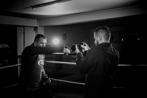 Powerful boxer showing punch technique against friend with camera